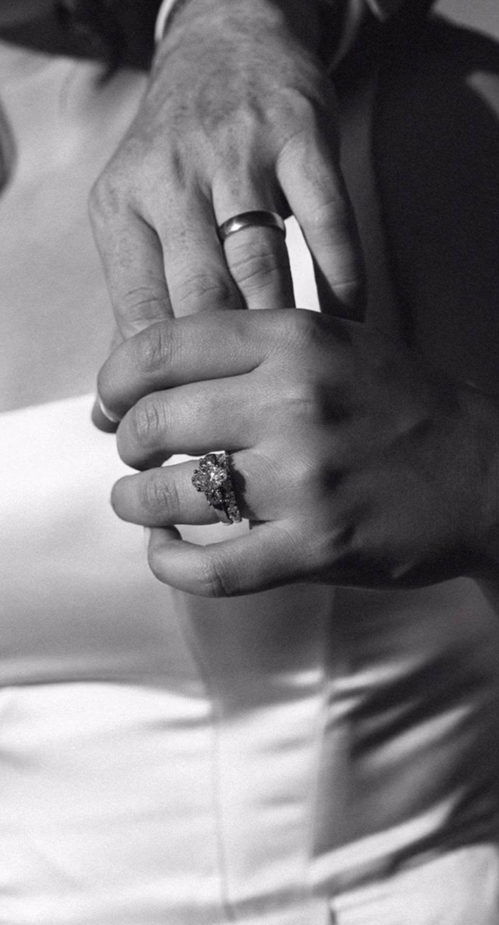 A couple's hands, the man wearing a white platinum wedding band, at Homsy Jewelers Boston