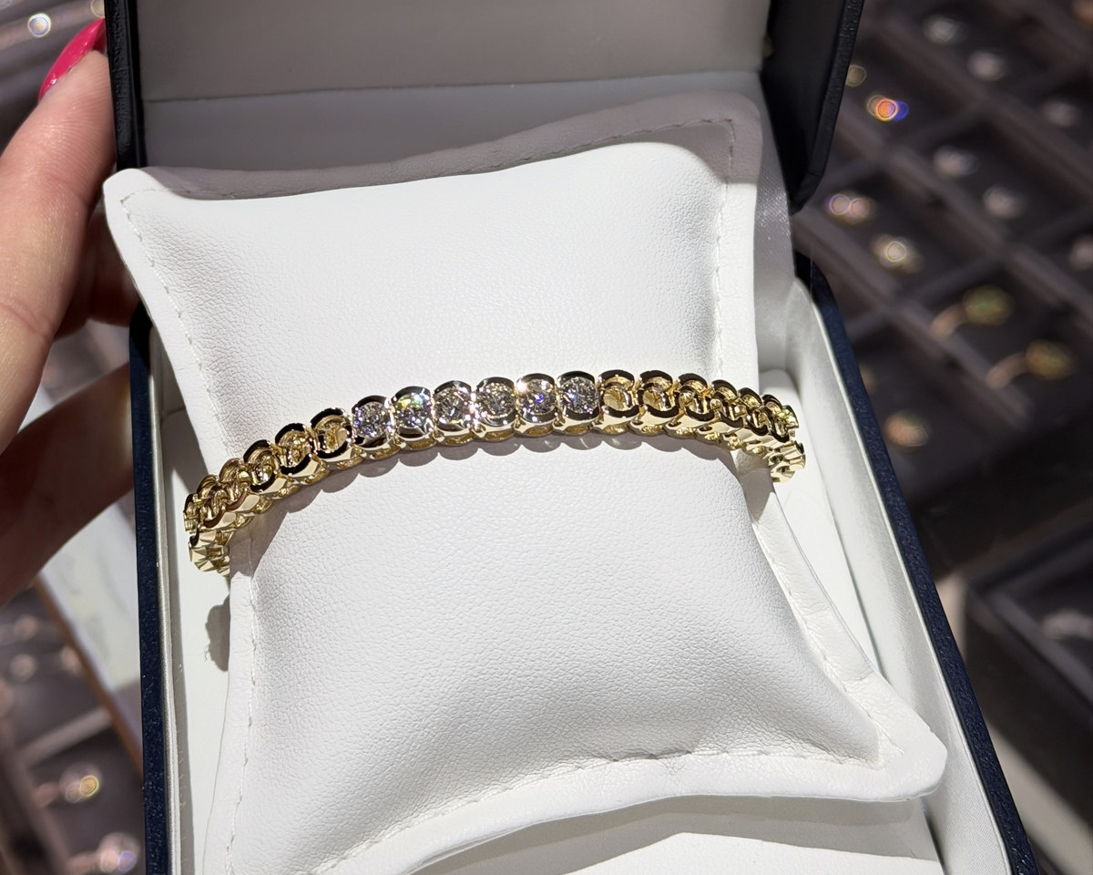 An open Homsy Jewelers box with a yellow gold half bezel Birdie Bracelet on the pillow, its first diamonds set and the empty settings waiting for the next birdies