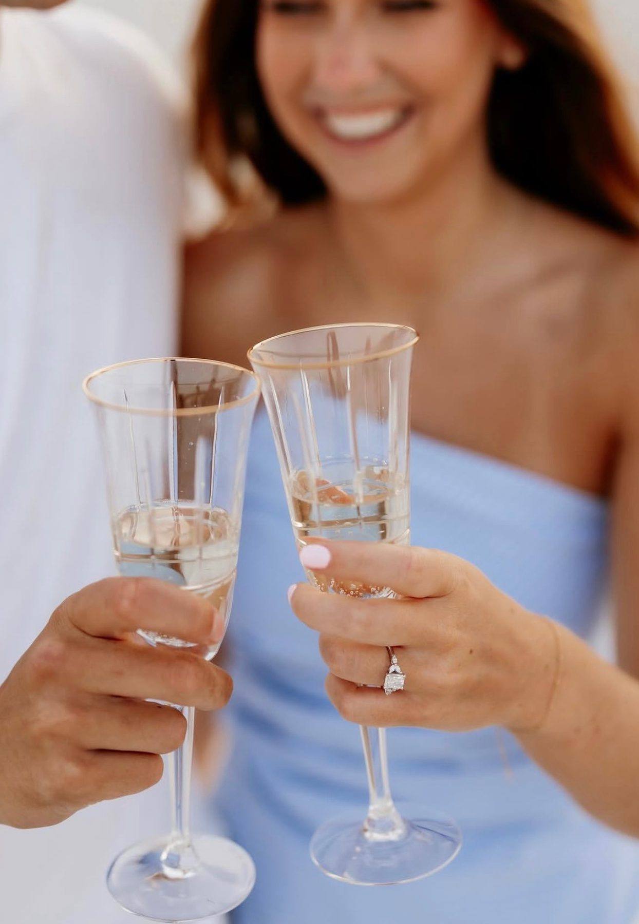 A couple toasting their engagement, her diamond ring from Homsy Jewelers
