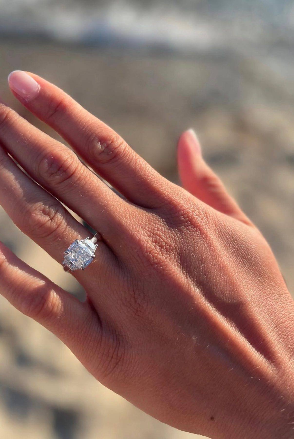 A newly engaged couple holding hands, her diamond ring from Homsy Jewelers in view