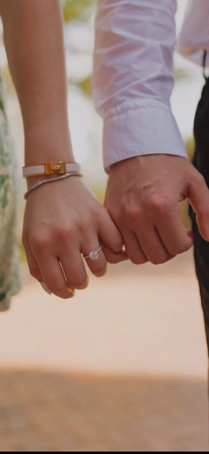 A couple's hands together, her solitaire engagement ring from Homsy Jewelers