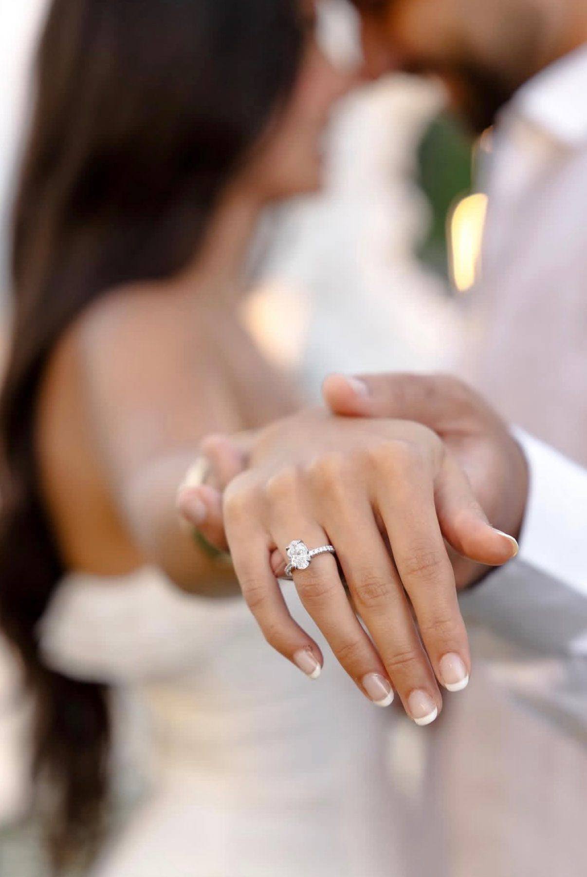 An engaged couple, her oval diamond engagement ring from Homsy Jewelers