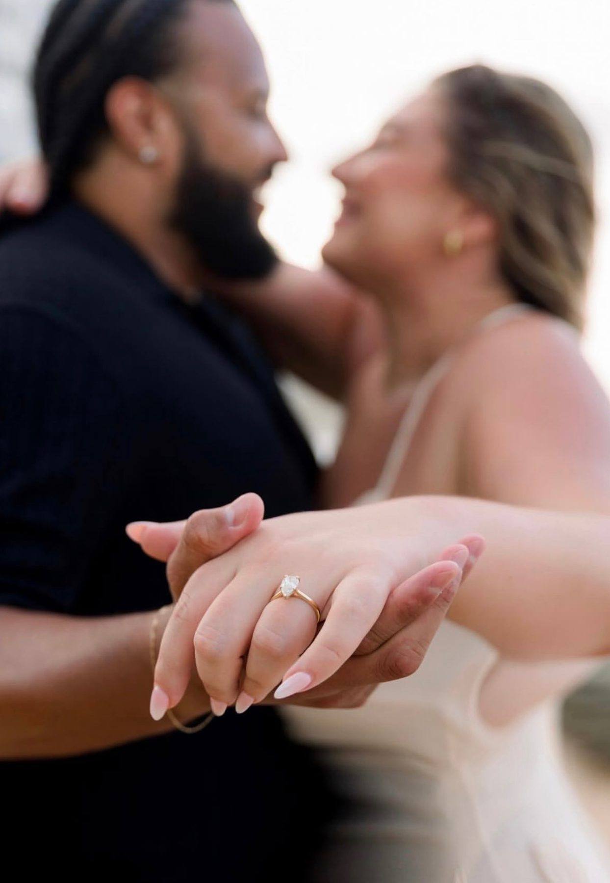 A newly engaged couple, her pear diamond ring from Homsy Jewelers with a bouquet