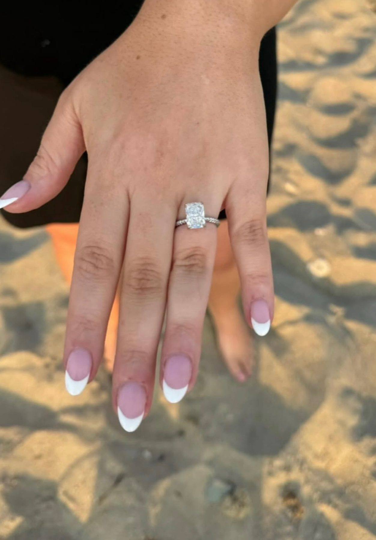 A radiant-cut diamond engagement ring from Homsy Jewelers worn at the beach