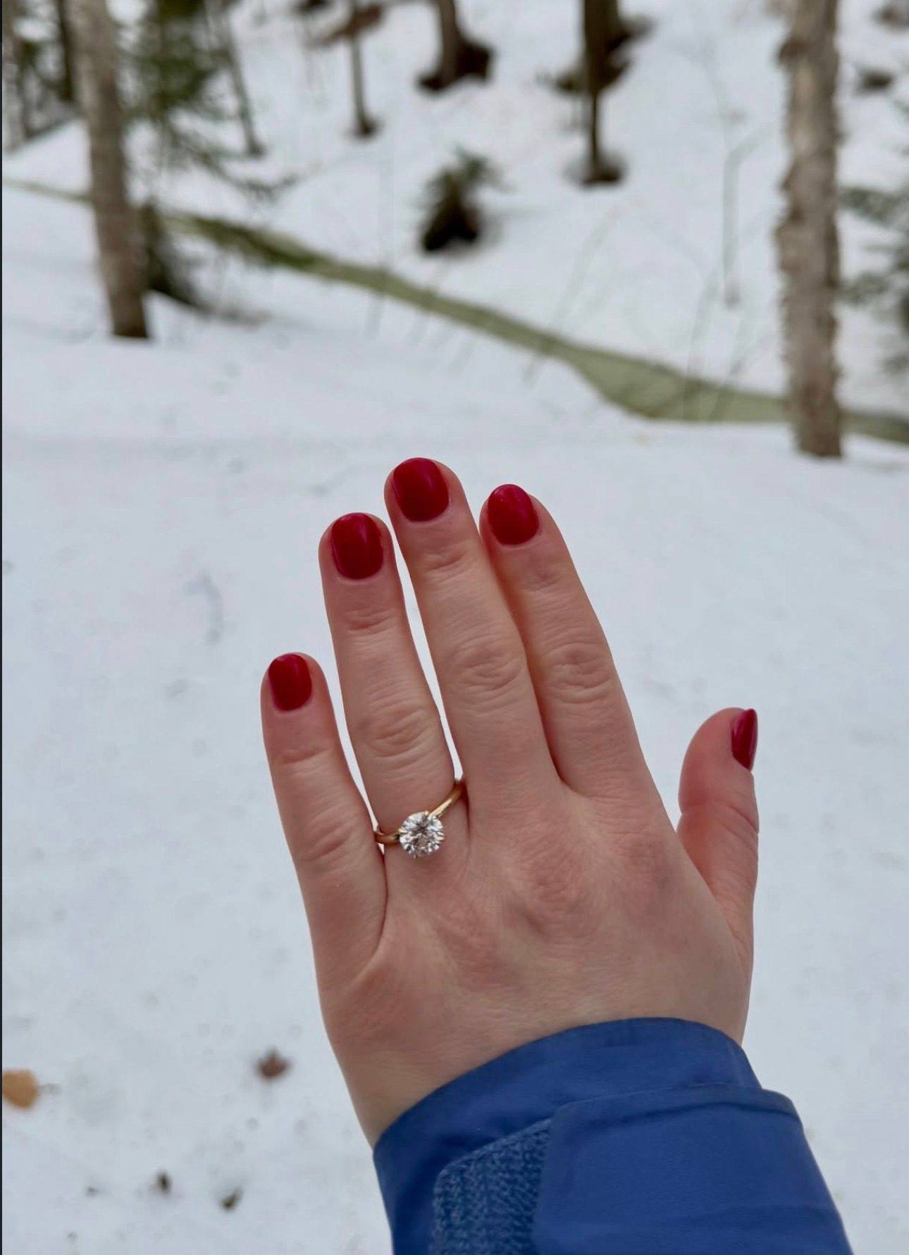 A hand wearing a solitaire diamond engagement ring from Homsy Jewelers